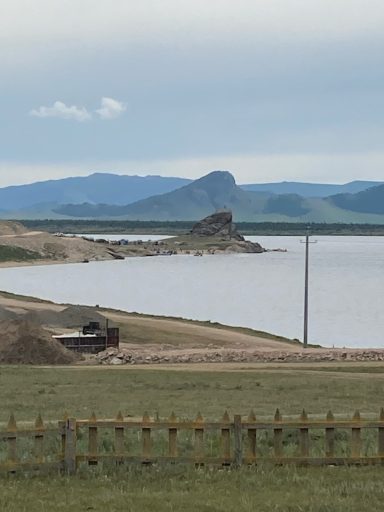 Blick auf den Terch Lake Weite Landschaft mit Wasser, Bergen und einem Fahrzeug am Ufer.